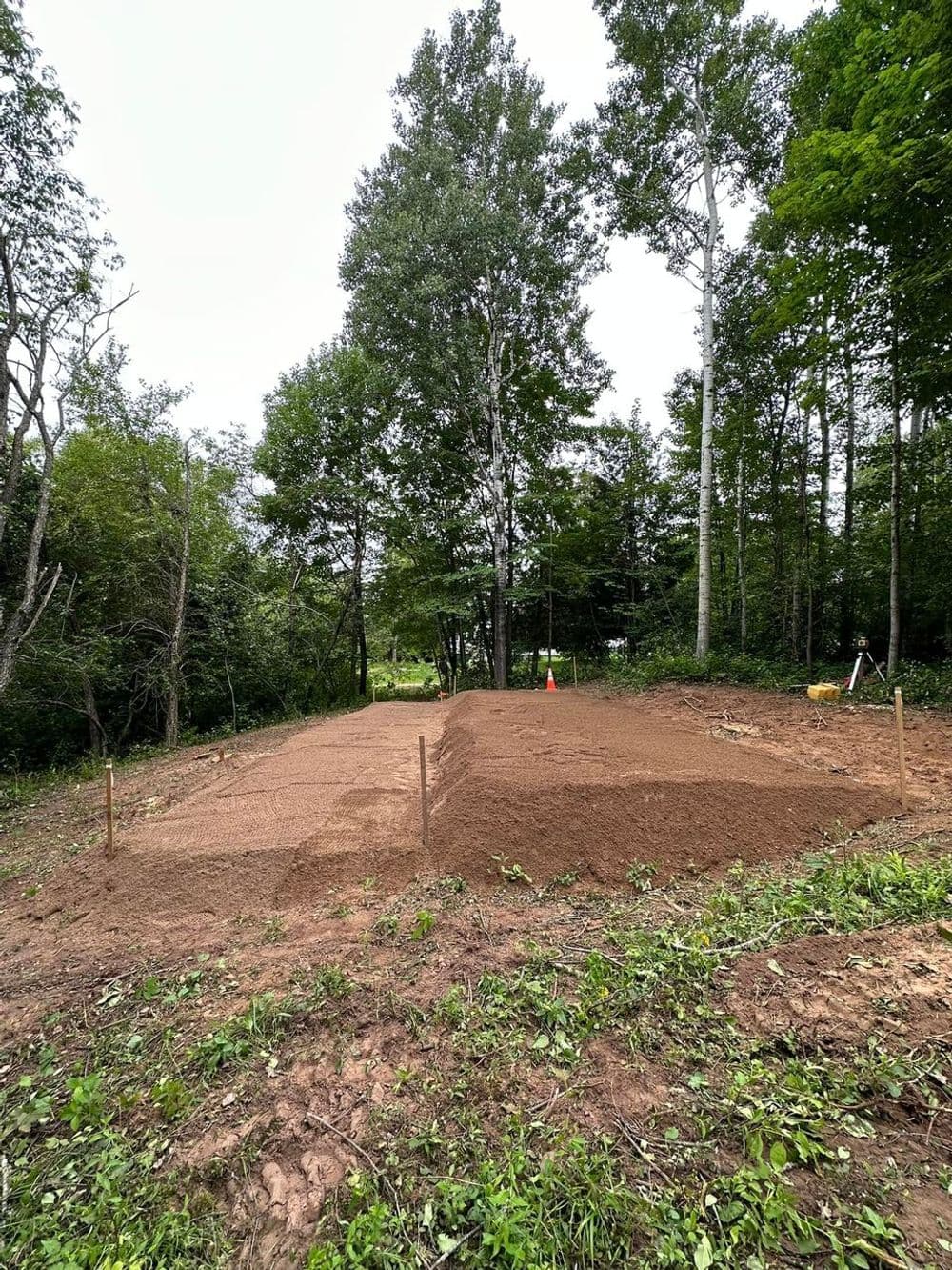 Prepared plot of land for construction, surrounded by trees and shrubs.